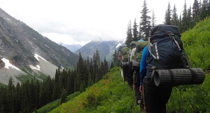 a group of teens crossing mountainous terrain on outdoor leadership course